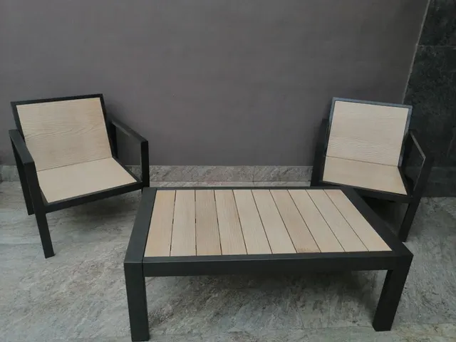 Dos sillones individuales de estructura oscura y una mesa de centro con cubierta de tablillas claras