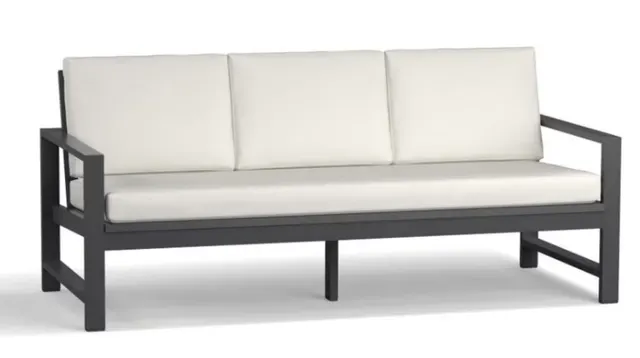 Sillón de tres plazas de estructura oscura con cojines blancos, imagen del catálogo