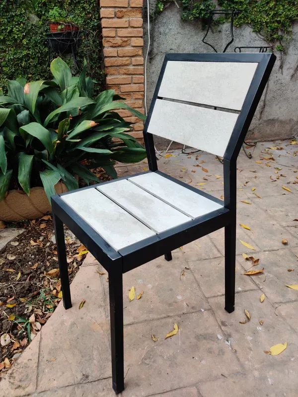 Silla de la línea Mishka Garden en un patio con plantas
